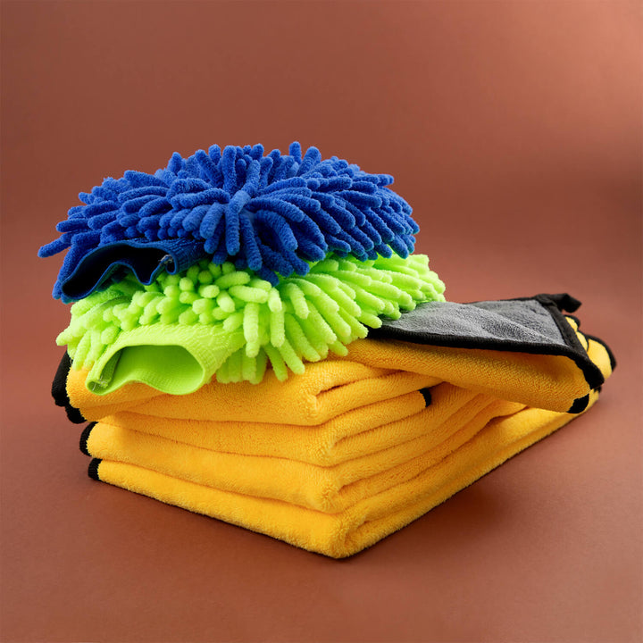 Stack of yellow microfibre cleaning cloths, microfiber, cleaning supplies, cleaning cloths with blue and green scrubber pads on a brown background