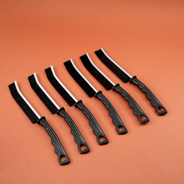 Set of black crevice cleaning tools, cleaning brush, microfibre, cleaning supplies with curved blades on an orange background