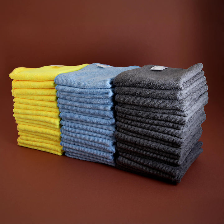 Stacks of yellow, blue, and gray microfibre cleaning cloths, microfibre, cleaning supplies on a brown background