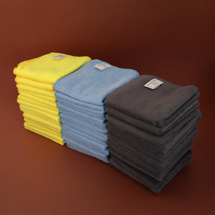 Stack of yellow, blue, and gray microfiber cloths, cleaning cloths, cleaning supplies, microfibre on a brown background
