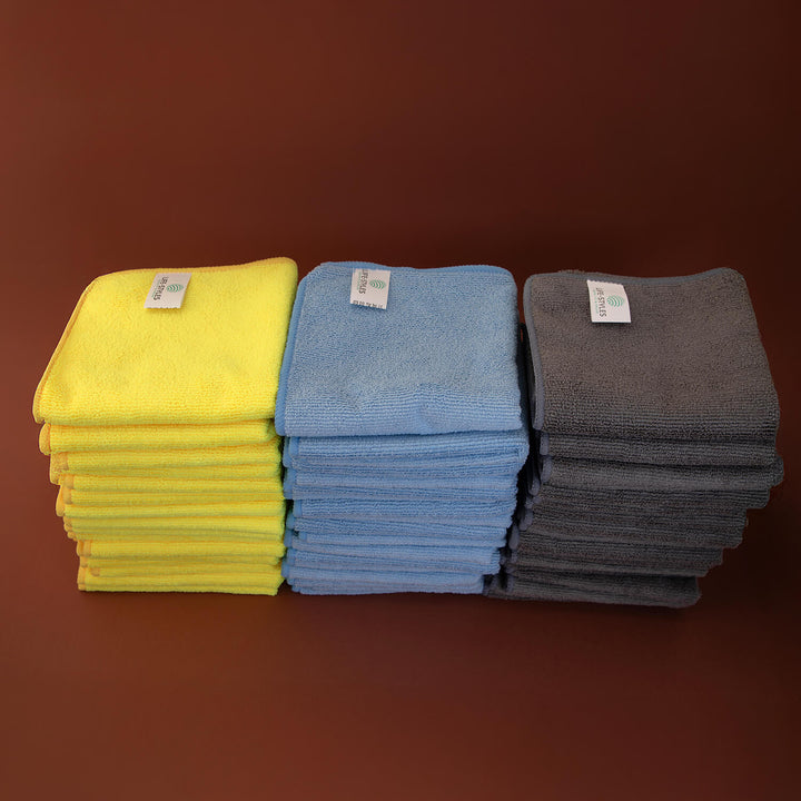 Stacks of yellow, blue, and gray microfibre cloths, cleaning cloths, ceaning supplies on a brown background