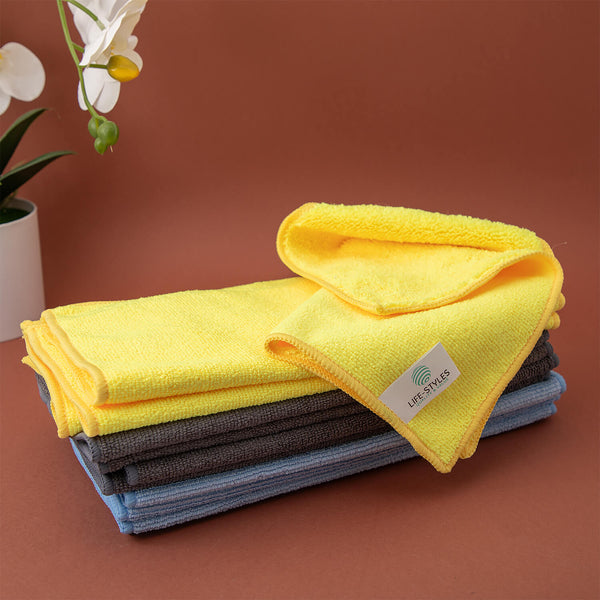 Stack of folded yellow, gray, and blue microfiber cloths, cleaning supplies, microfibre cloths, cleaning cloths with a visible brand logo on a brown background.