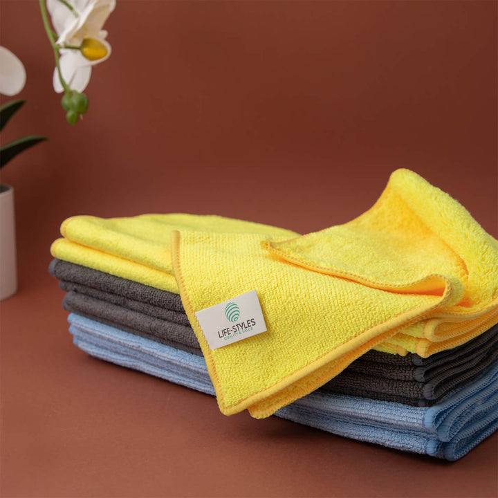 Stack of folded microfiber cloths, microfibre cloths, cleaning cloths, cleaning supplies with a visible brand label on a brown surface.