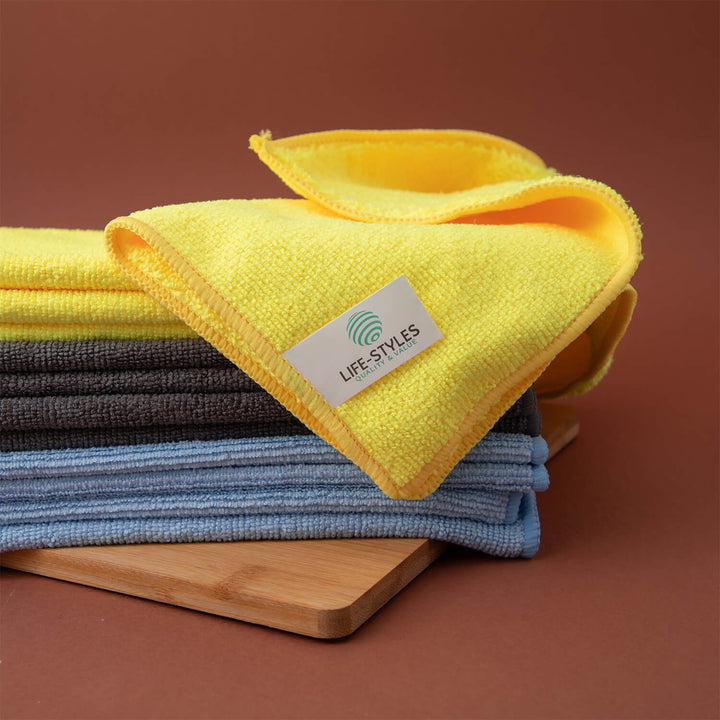 Stack of folded microfiber cloths, microfibre cloths, cleaning cloths, cleaning supplies with a Life-Styles label on a wooden board against a brown background