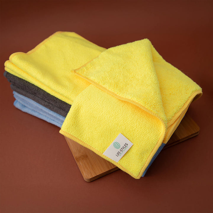 Set of yellow microfiber cloths, cleaning supplies, cleaning cloths, microfibre on a wooden block with a brown background