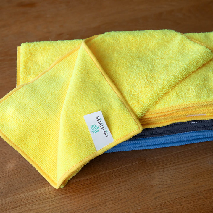 Yellow and blue microfiber cloths, microfibre cloths, cleaning supplies, cleaning cloths with a visible brand label on a wooden surface