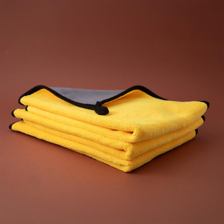 Stack of 3 yellow microfibre cloths, cleaning supplies, cleaning cloths with a brown background