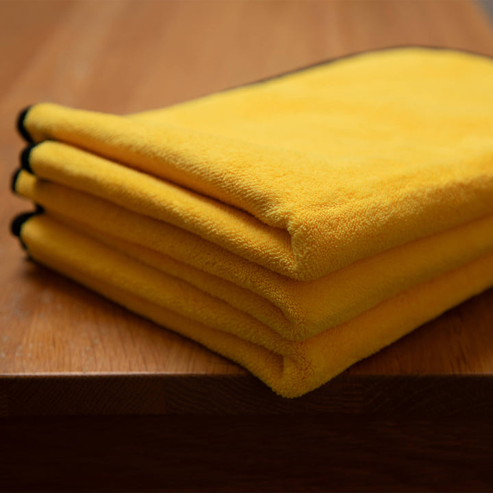 Stack of yellow microfibre cleaning cloths, microfibre, cleaning cloths, cleaning supplies on a wooden surface