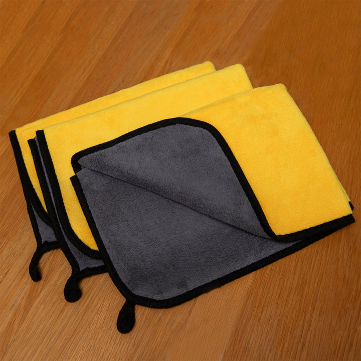 Two yellow microfiber cloths, microfibre, cleaning cloths, cleaning supplies and one gray microfiber cloth on a wooden surface