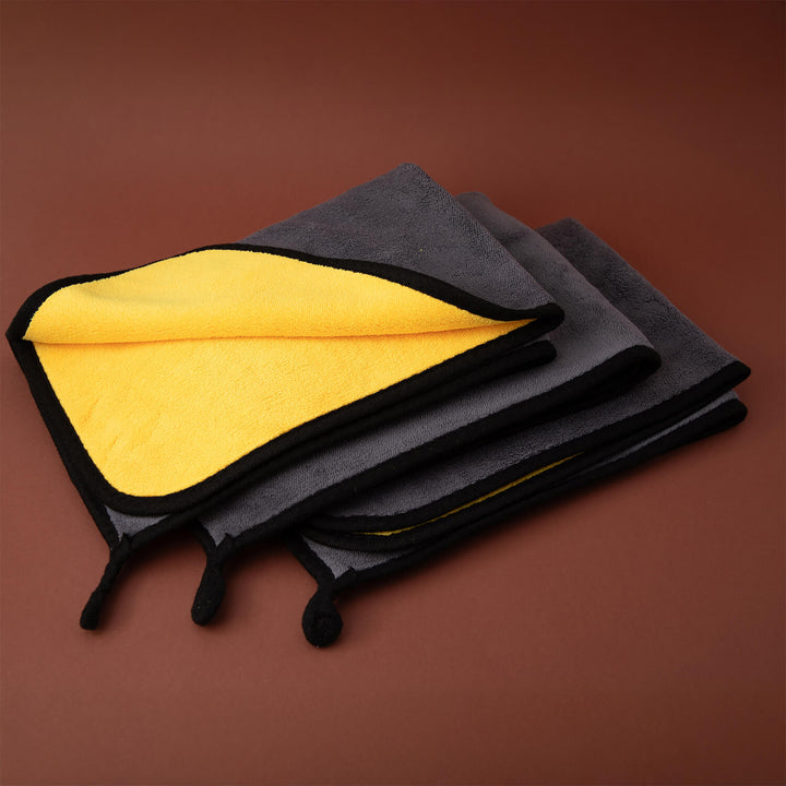 Black and yellow folded cleaning supplies, microfibre cleaning cloths, microfibre on a brown background