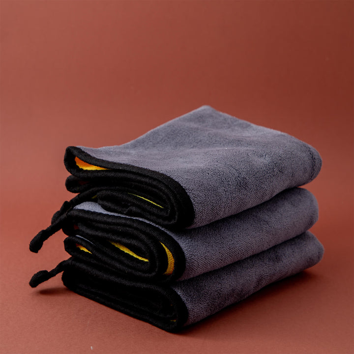 Stack of folded gray microfibre cleaning cloths, cleaning supplies, cleaning cloths on a brown background