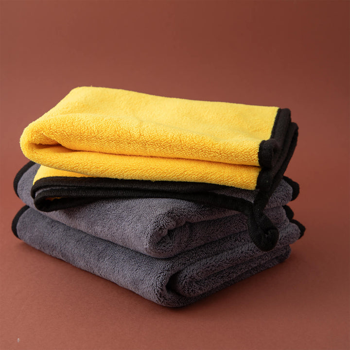 Stack of yellow and gray microfibre cleaning cloths, microfibre, cleaning cloths, cleaning supplies on a brown background